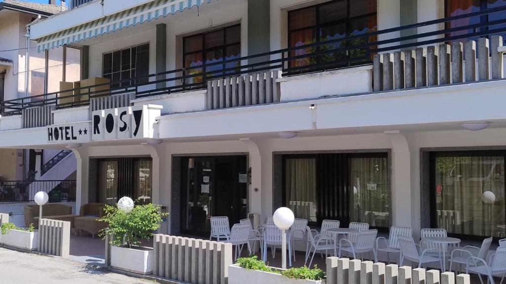 a building with white chairs and tables and windows at Hotel Rosy in Bellaria-Igea Marina