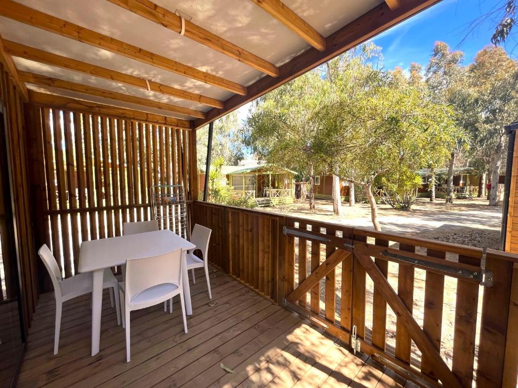 une terrasse en bois avec une table et des chaises blanches dans l&#39;établissement Camping La Pinède, à Calvi