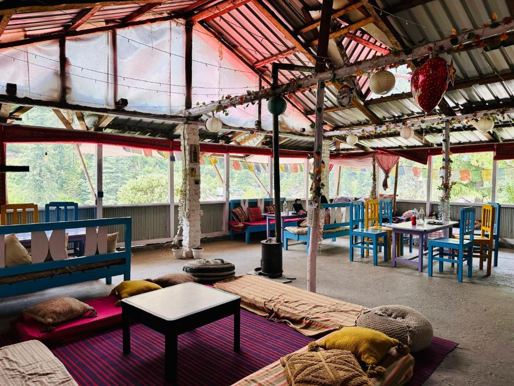 Großes Zimmer mit Sofa, Tischen und Fenstern in der Unterkunft Hostel 360 Degree Jibhi in Jibhi