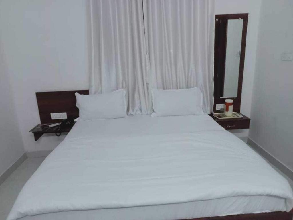 a large white bed in a room with a mirror at OYO Hotel HR International Restaurant 