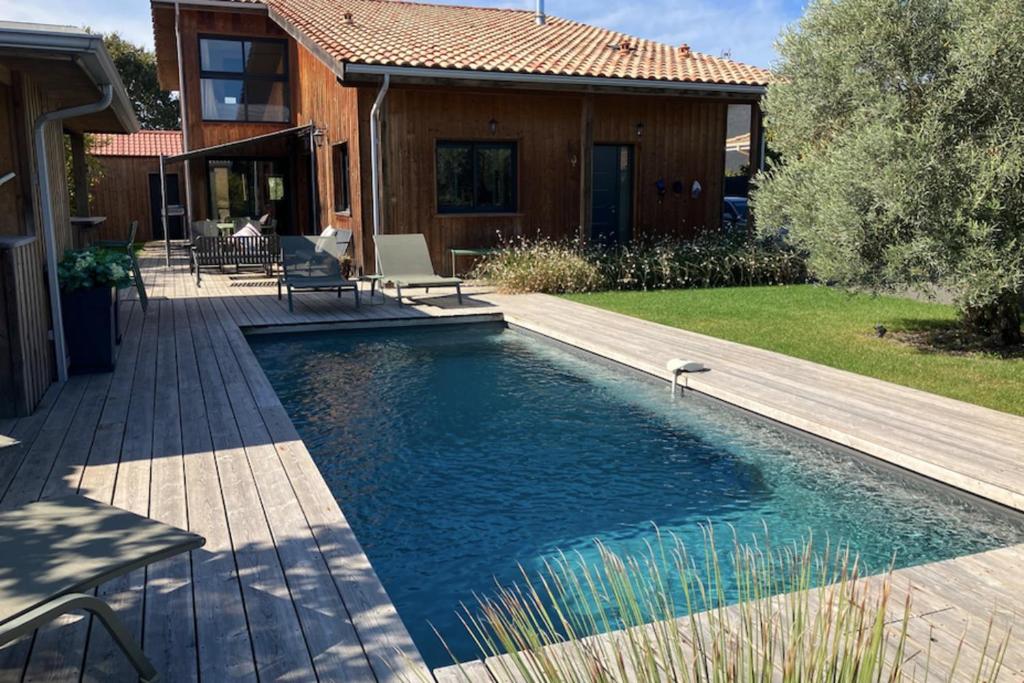 uma piscina com um deque e uma casa em Sumptuous Cap Ferret Style House em La Teste-de-Buch