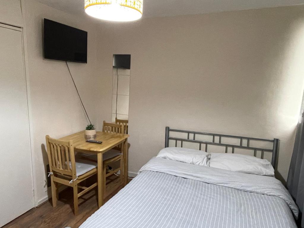 um quarto com uma cama e uma mesa com uma televisão em Comfortable double room em Londres