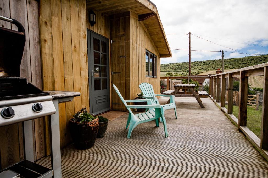 a wooden deck with two chairs and a stove at Poachers Perch At Tapnell Farm in Yarmouth
