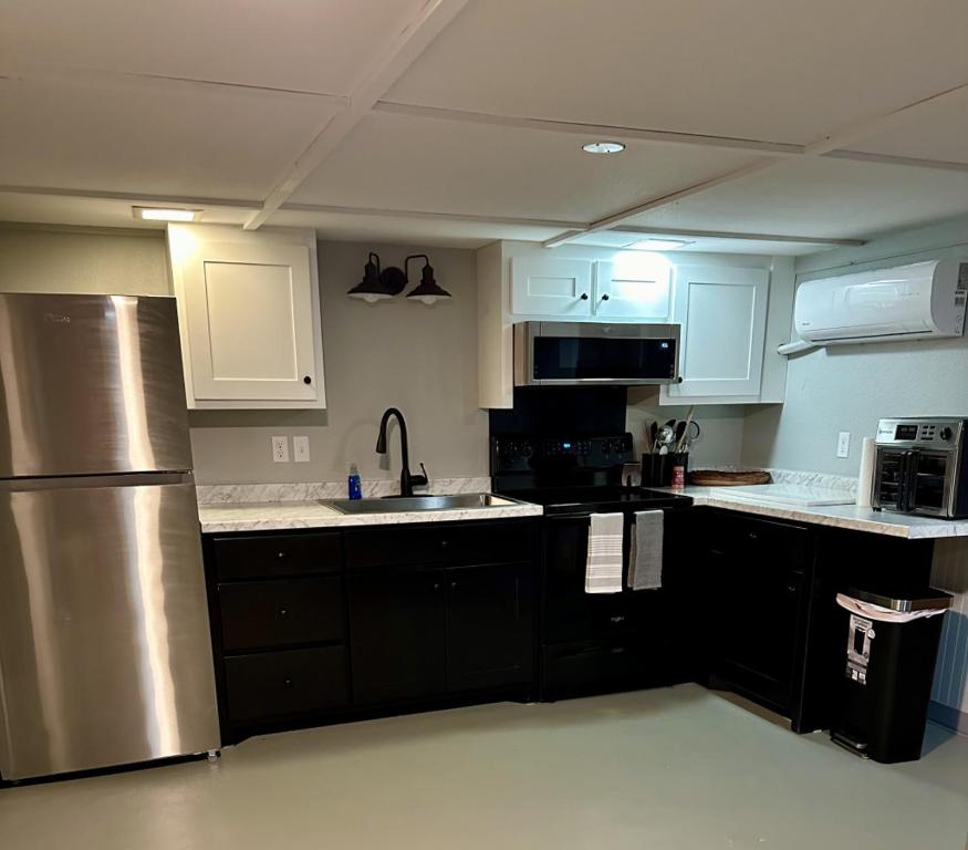 a kitchen with black cabinets and a stainless steel refrigerator at Amys Place Remolded 4 Bedroom near Arkansas Tech in Russellville