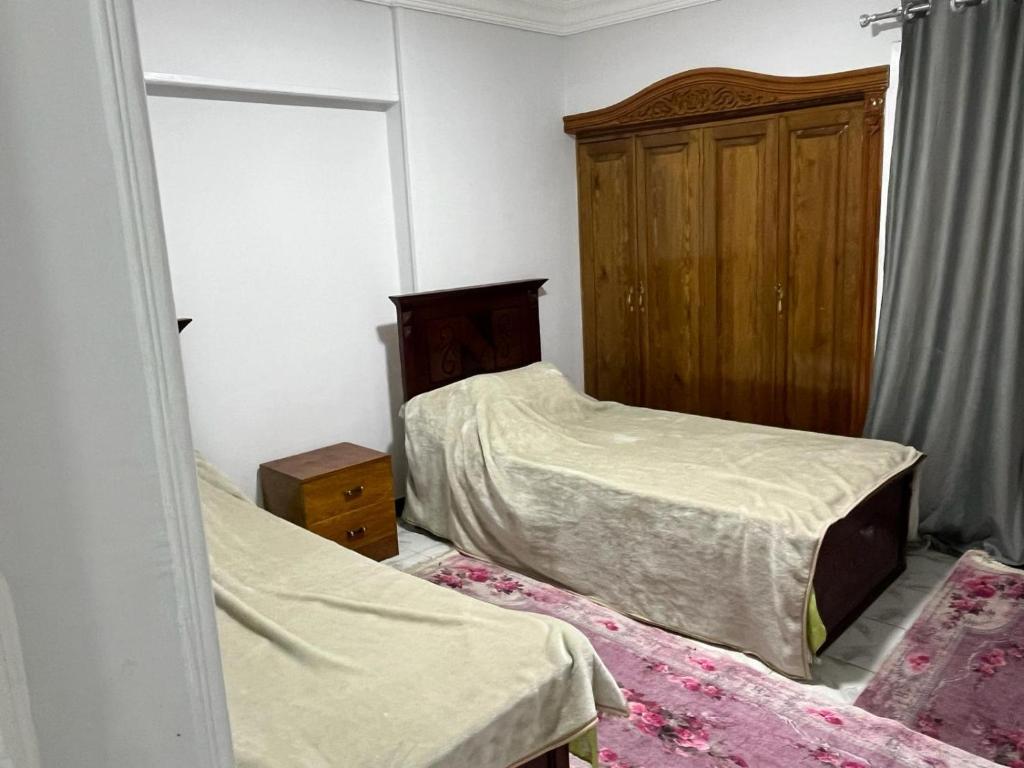 - une chambre avec 2 lits et une armoire en bois dans l'établissement Nice apartment in mostafa kamel city square, à Alexandrie