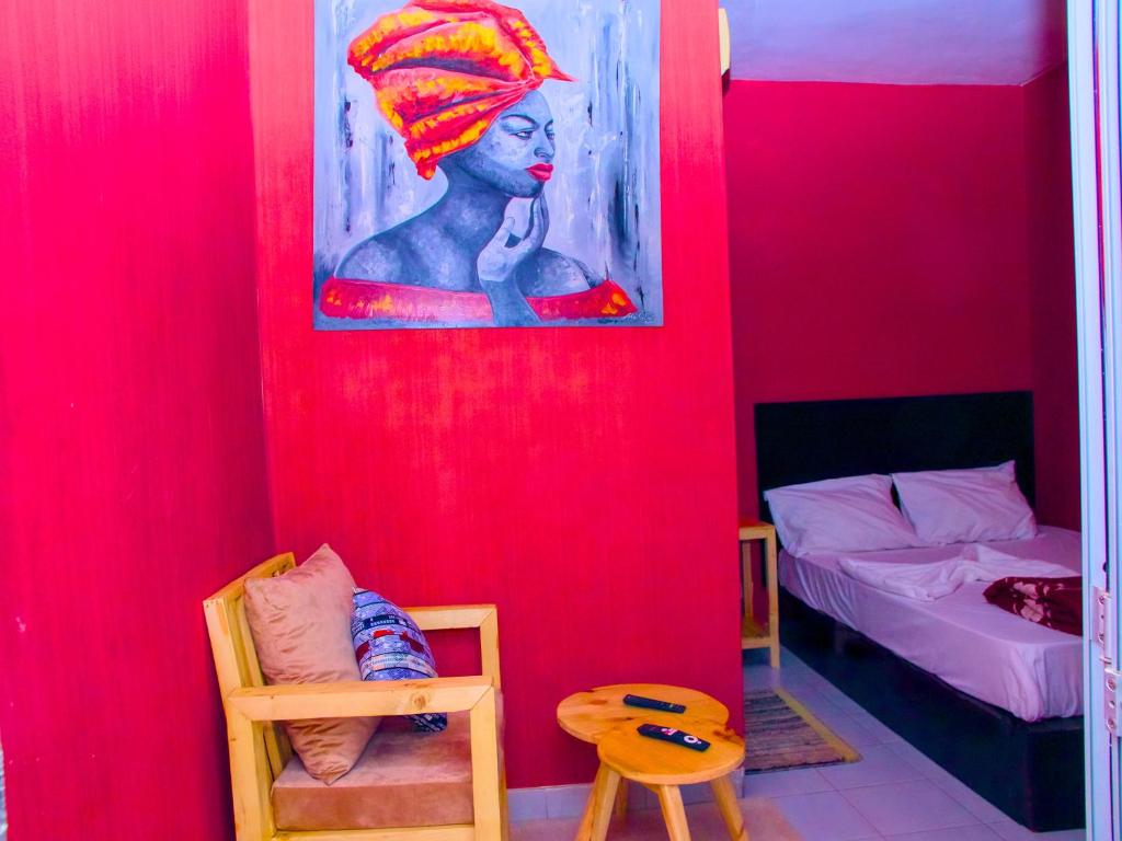 een kamer met een rode muur met een schilderij van een vrouw bij Dakar International House in Dakar