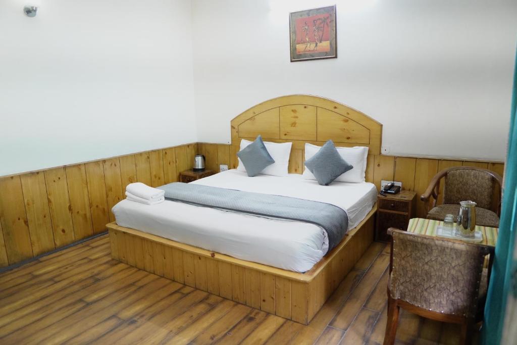 a bedroom with a large bed and a desk with a chair at Ramta Jogi Hotel & Stays in Manāli