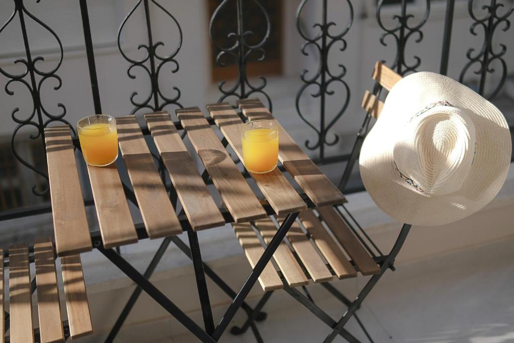 two glasses of orange juice on a bench with a hat at DUOMO City Center Suites, 1st Floor in Heraklio Town