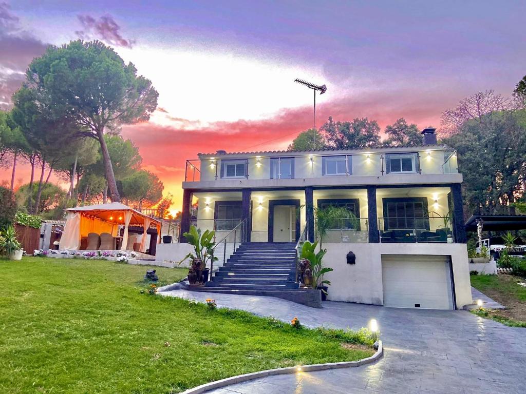 uma grande casa branca com um pôr-do-sol ao fundo em Villa Vip em Pelayos de la Presa