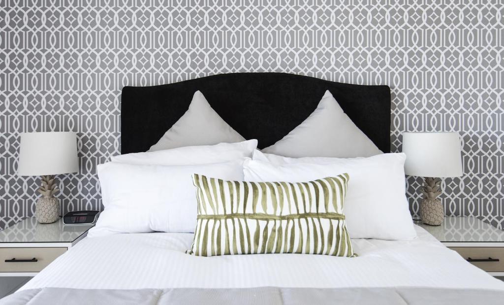 a white bed with a black headboard and two lamps at Riviera Mackay in Mackay