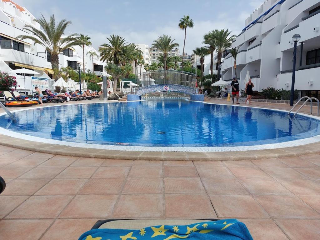 ein großer blauer Pool mit Palmen und Gebäuden in der Unterkunft Aton Holiday Colon II Playa De Las Américas in Arona