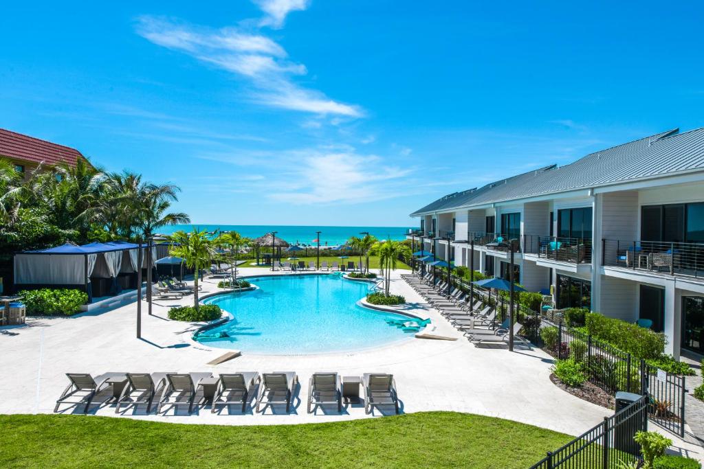 an image of a resort pool with chairs and the ocean at Anna Maria Beach Resort in Holmes Beach