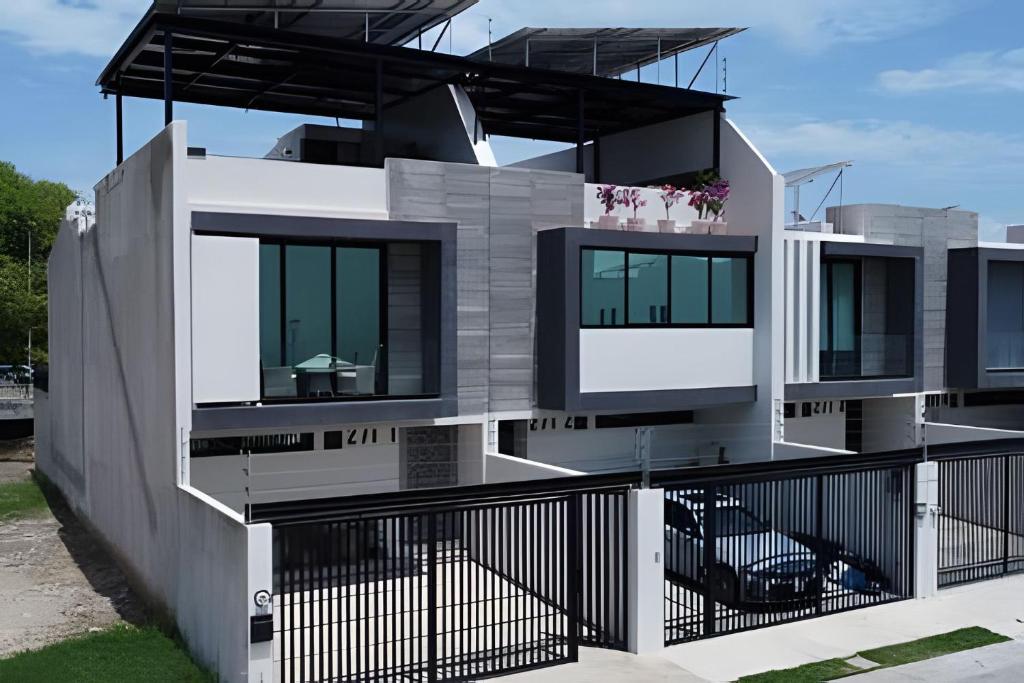 une grande maison blanche avec une clôture noire dans l'établissement New! Fluvial Casa con Alberca, à Bucerías