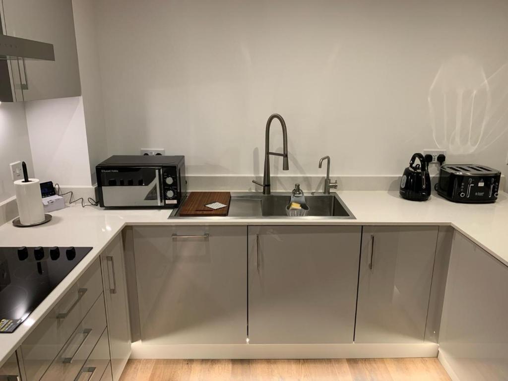 uma cozinha com um lavatório e um micro-ondas em Reliance Apartment em Harlow