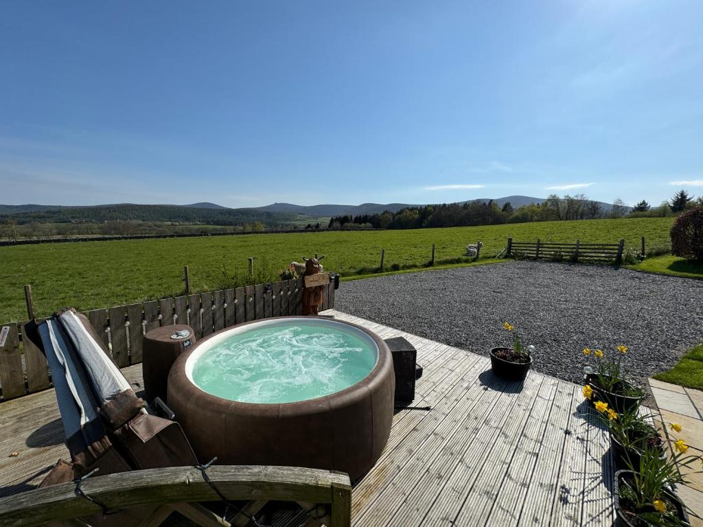 bañera de hidromasaje en una terraza con vistas a un campo en Drumhead Cottage Finzean, Banchory Aberdeenshire Self Catering with Hot Tub, en Finzean