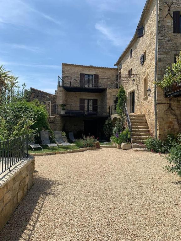 Un grand bâtiment en briques avec un escalier se trouve devant. dans l'établissement MAs en pierre 17ème piscine exposition sud proche uzès, à Aubussargues