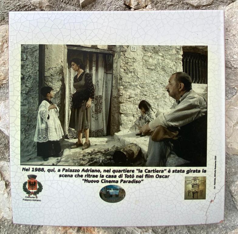 an old picture of a man sitting in front of a house at Affittacamere La Cartiera in Palazzo Adriano