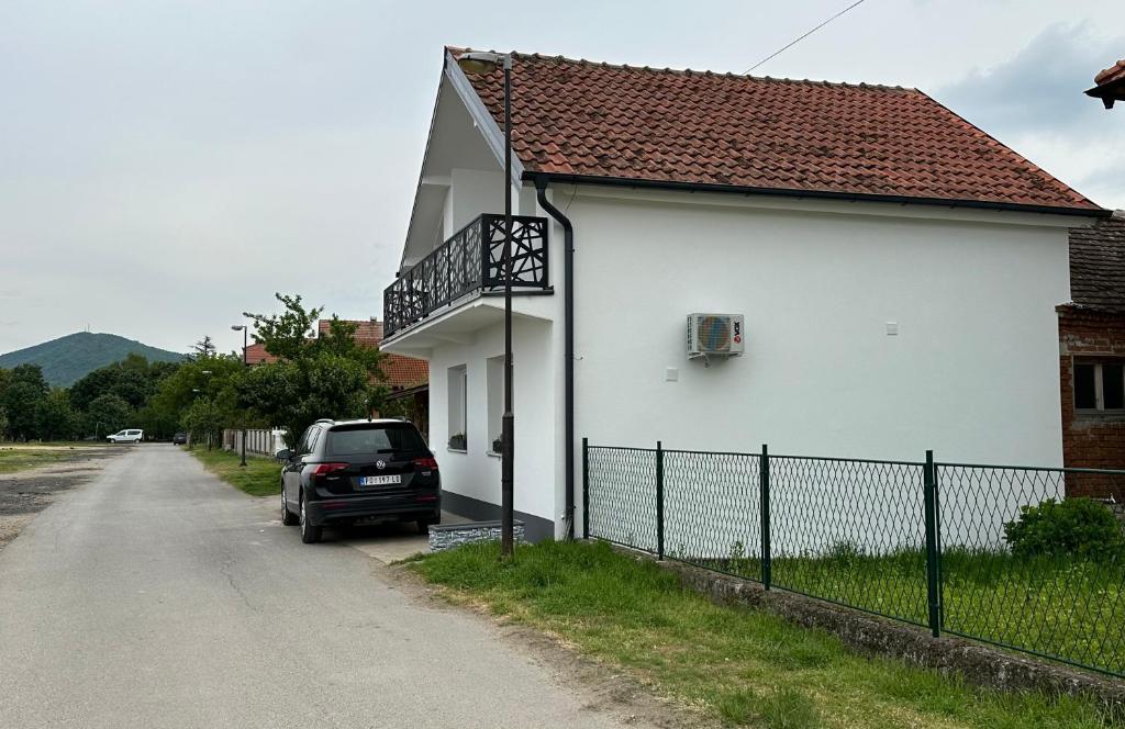 a car parked next to a white house at Košava in Golubac