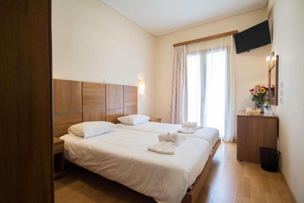 1 dormitorio con 2 camas y ventana grande en THOLOS HOTEL, en Delfos