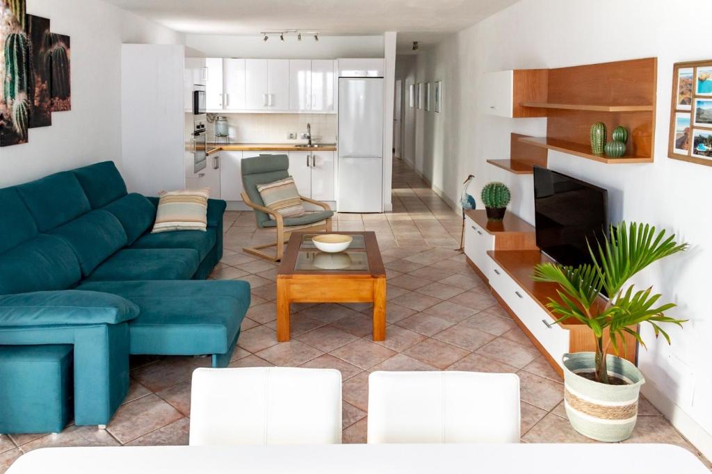 a living room with a blue couch and a kitchen at Puerto del Carmen Las caracolas Acogedor espacioso y luminoso apartamento cerca del mar in Puerto del Carmen