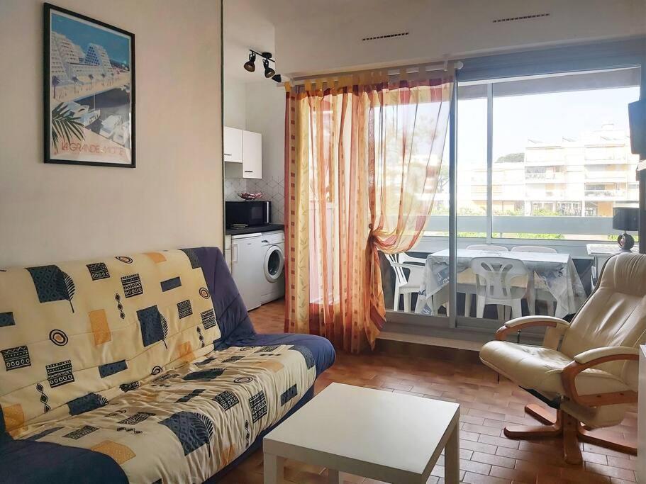 un salon avec un canapé, une table et une fenêtre dans l'établissement Nouveau! Studio centre-ville au calme, à La Grande Motte