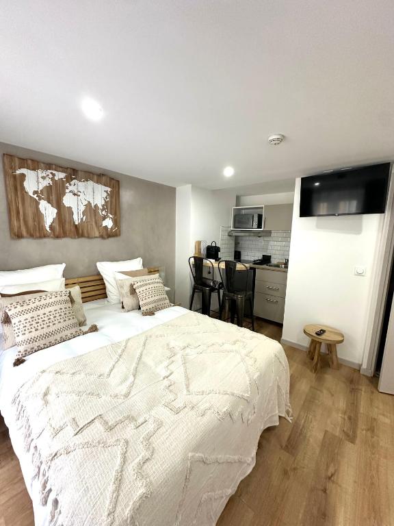 une chambre avec un grand lit blanc et une cuisine dans l'établissement Hôtel Résidence A la Buttes aux Cailles, à Paris