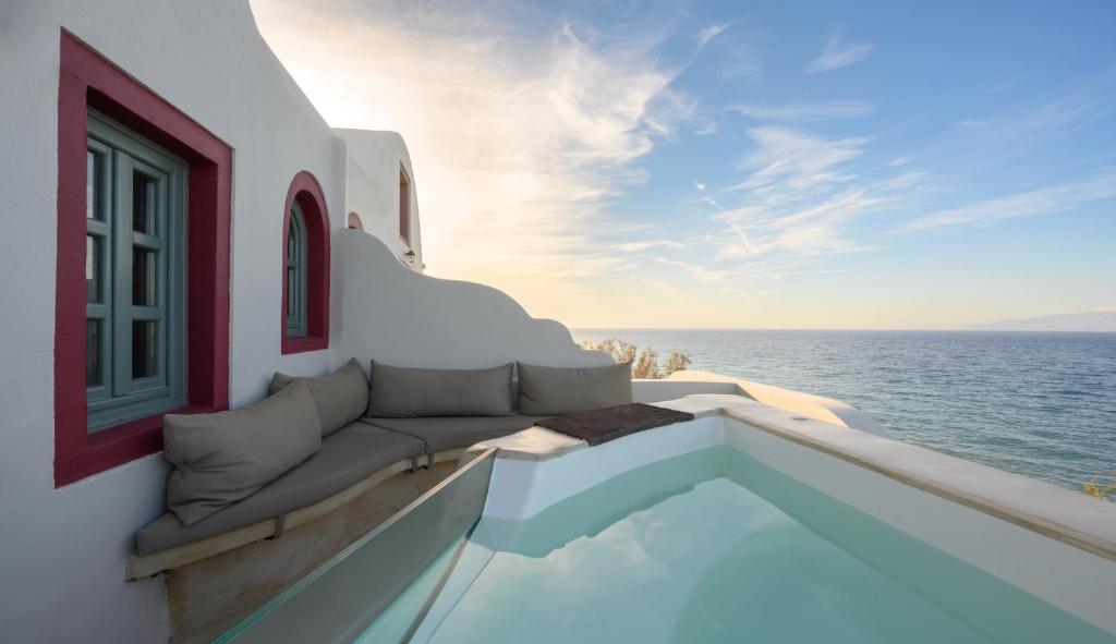 a balcony with a couch and a window overlooking the ocean at Michelangelo Beach Villa in Oia