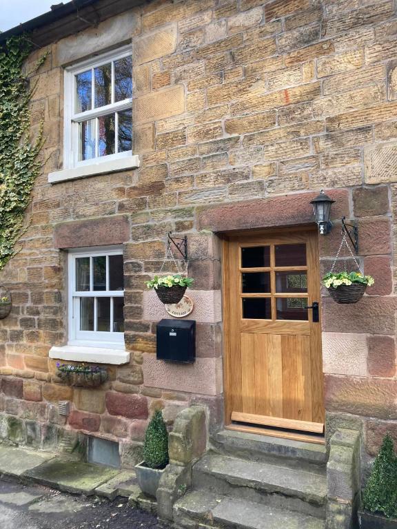 a stone house with a wooden door and two windows at Mill Cottage, Upper Hulme in Upper Hulme