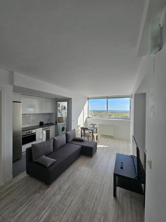 Cómodo apartamento en Madrid في مدريد: غرفة معيشة مع أريكة سوداء ومطبخ
