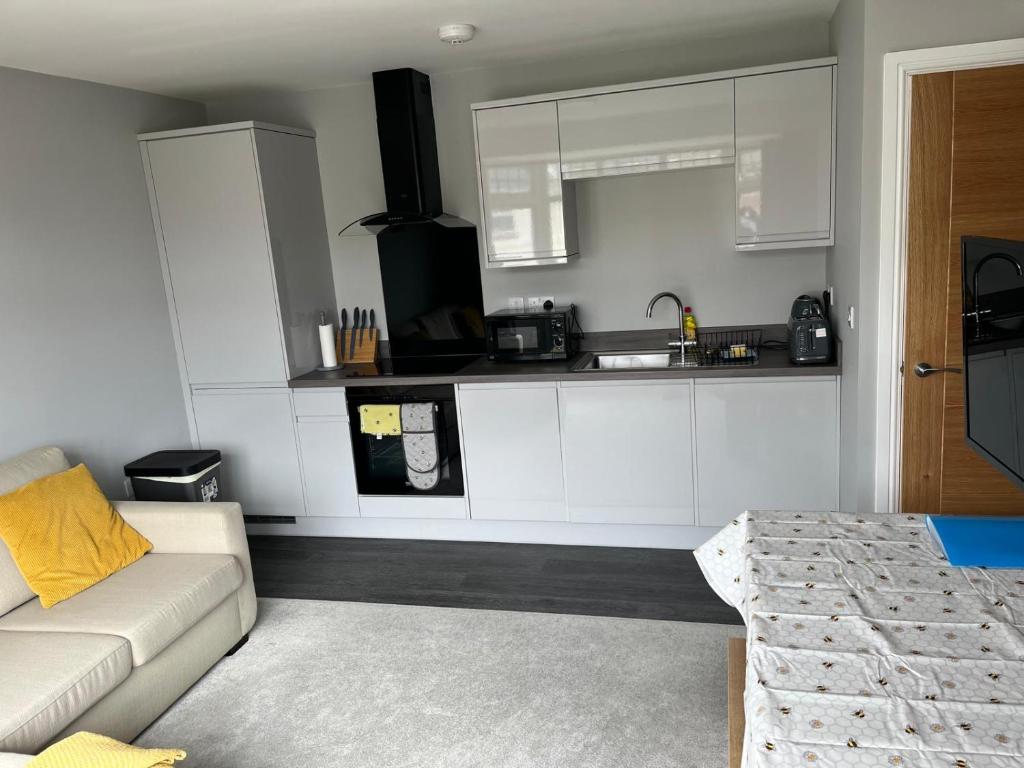 een woonkamer met een bank en een keuken bij New one bed 1st floor flat close to the beach in Southbourne