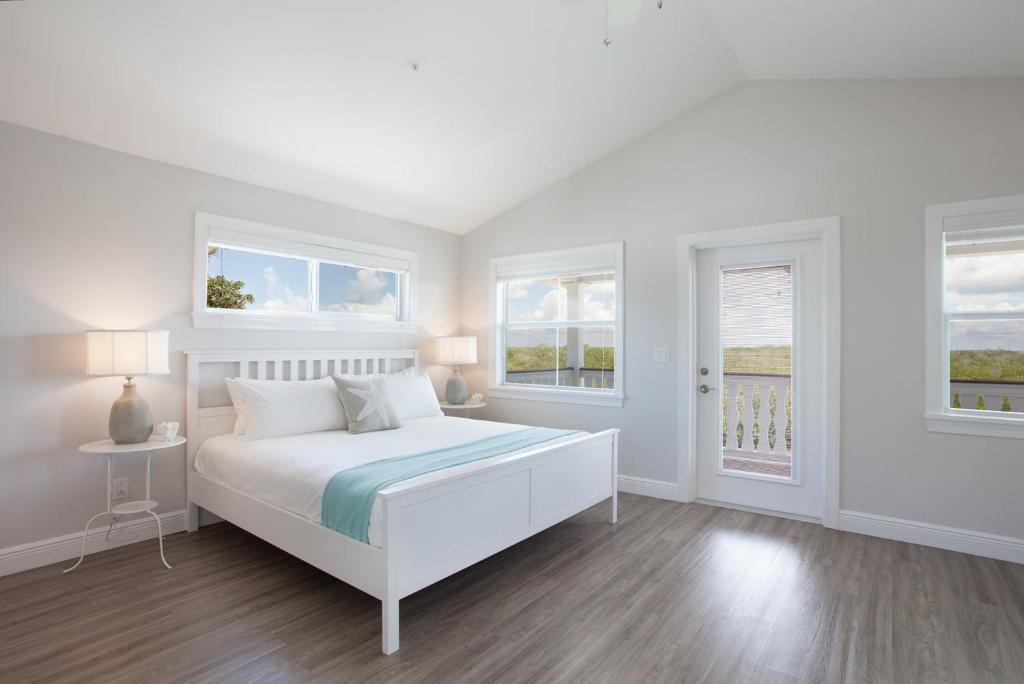 a white bedroom with a bed and two windows at Isla Key Kiwi - Waterfront Boutique Resort, Island Paradise, Prime Location in Islamorada