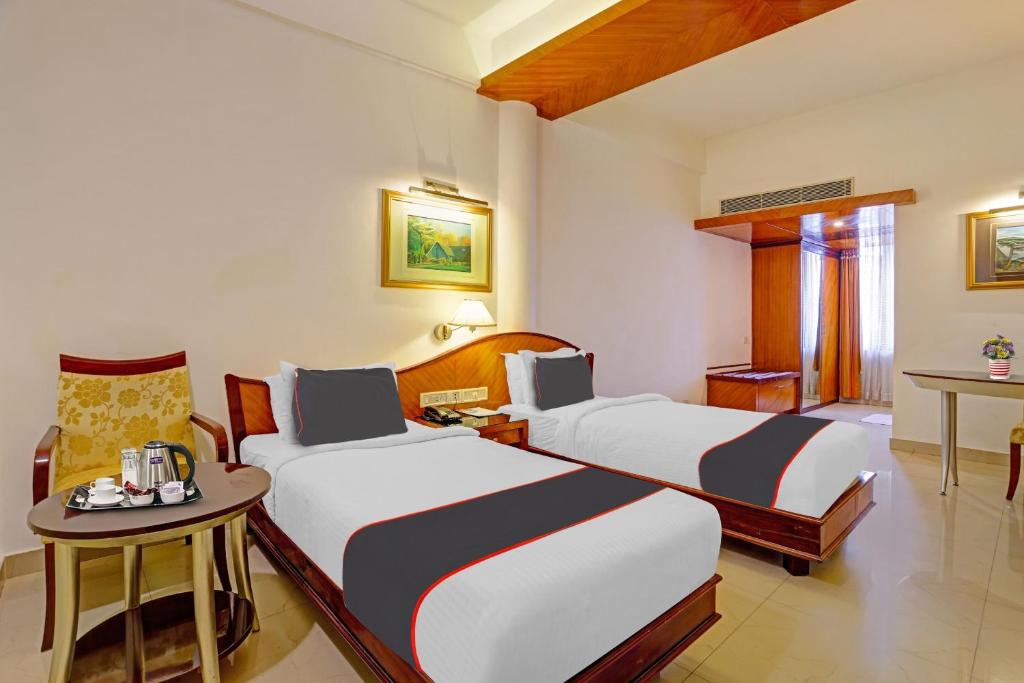 Habitación de hotel con 2 camas y mesa en Hotel Indraprastha, en Trivandrum