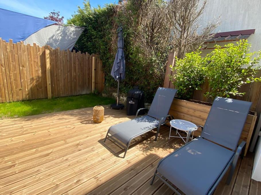 2 chaises et un parasol sur une terrasse en bois dans l'établissement Maison proche du centre Pornic, à Pornic