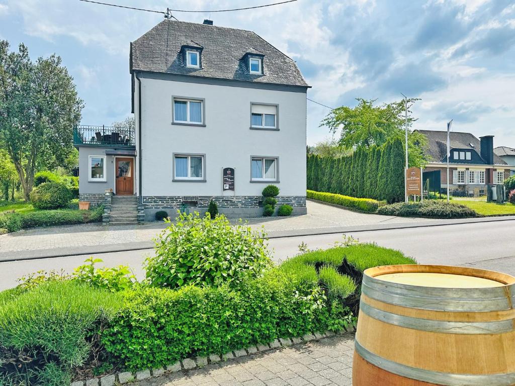 a white house with a barrel in front of it at Ferienwohnungen Weingut Kilburg in Brauneberg