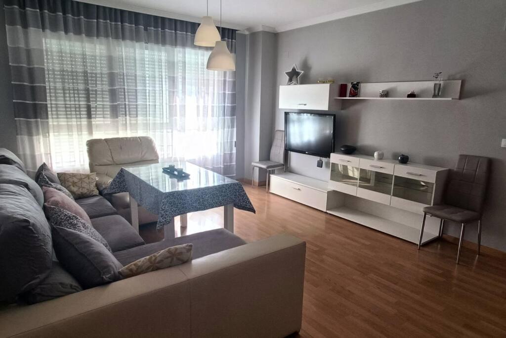een woonkamer met een bank, een tafel en een tv bij Apartamento con terraza 2 hab. in Alcalá la Real