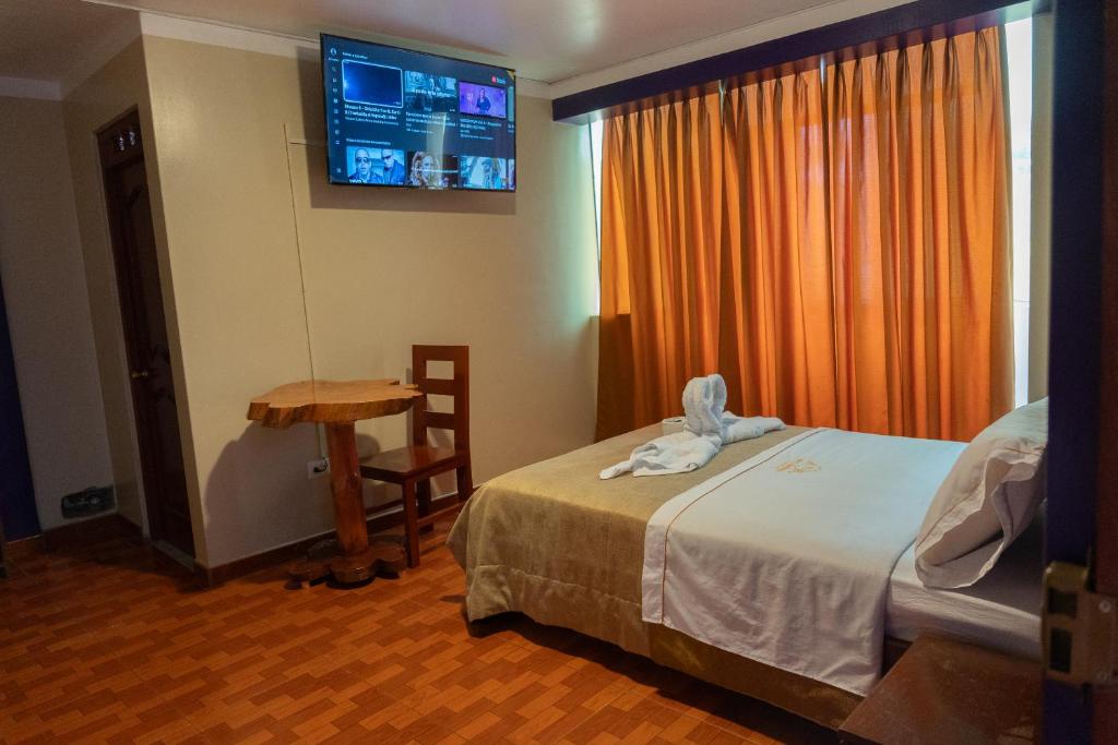 1 dormitorio con cama, mesa y TV en Hotel California, en Chachapoyas