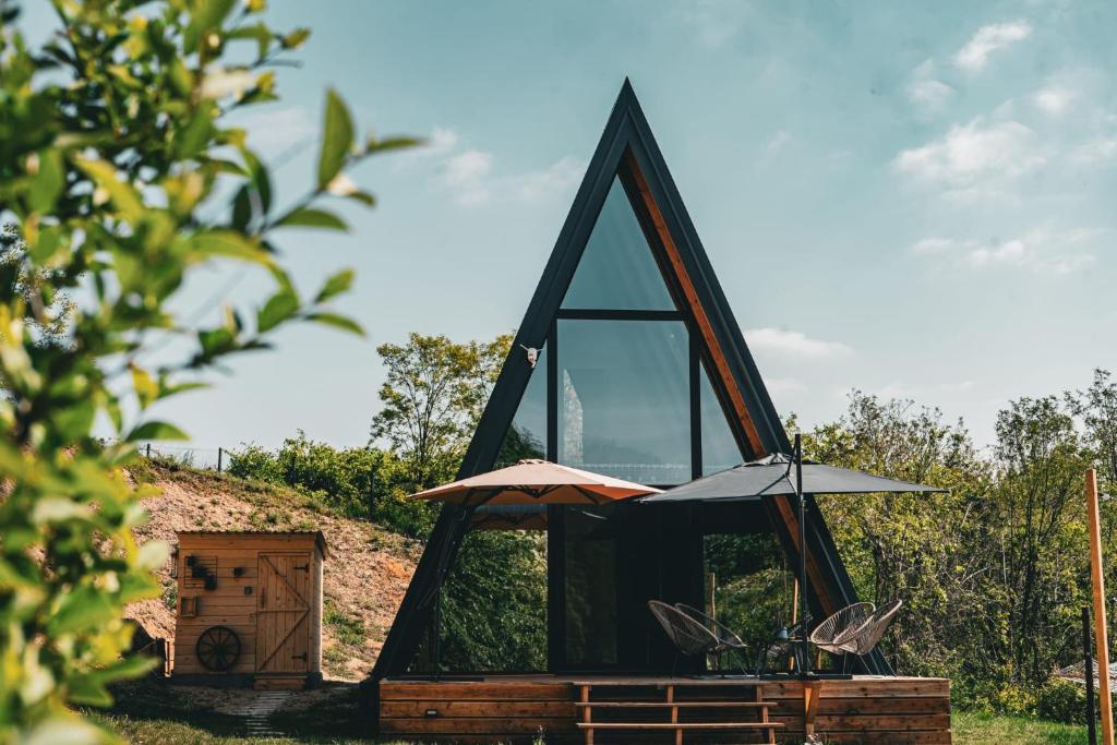 una casa di vetro con tavolo e ombrellone di Sunny A Frame in National Park Fruska Gora - Vrdnik a Vrdnik