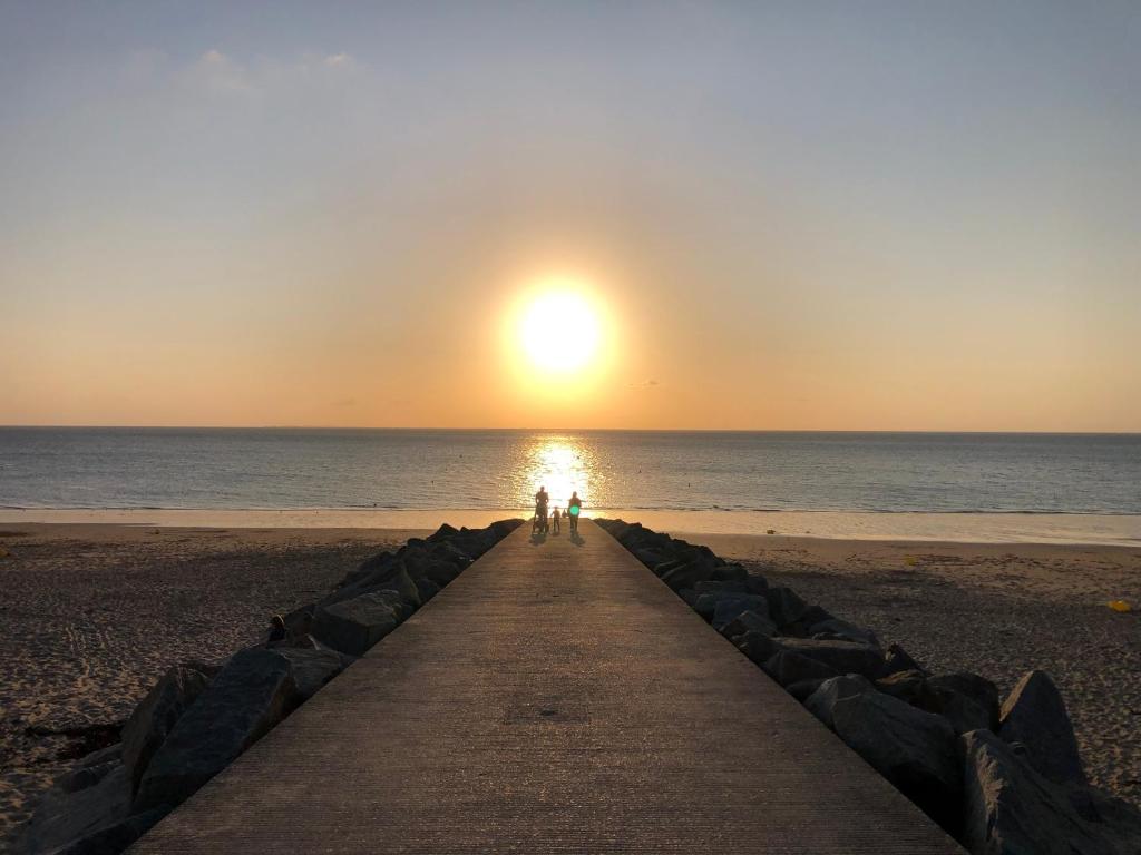 deux personnes debout sur une jetée à la plage dans l'établissement Gite Cottage Le Giré, à Hudimesnil