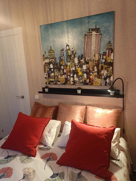 a bed with two red pillows and a painting above it at BEACH&GARDEN in Málaga