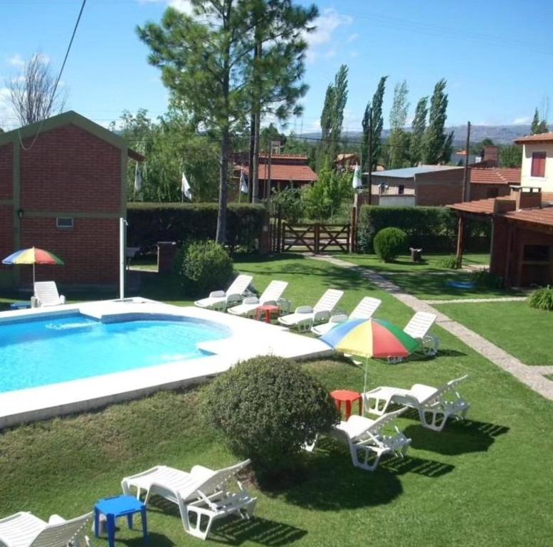 a pool with chairs and umbrellas in a yard at Complejo Cantonavi in Mina Clavero