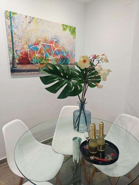 a glass table with a vase of flowers and a painting at BEACH&GARDEN in Málaga