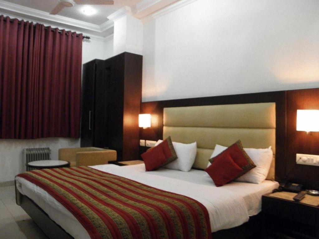 a hotel room with a large bed with red pillows at Hotel Chanchal Continental in New Delhi