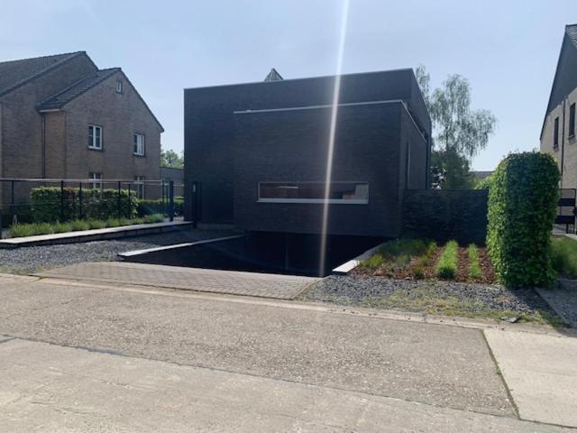 a black house with a building in a yard at 't Veldje in Tongeren
