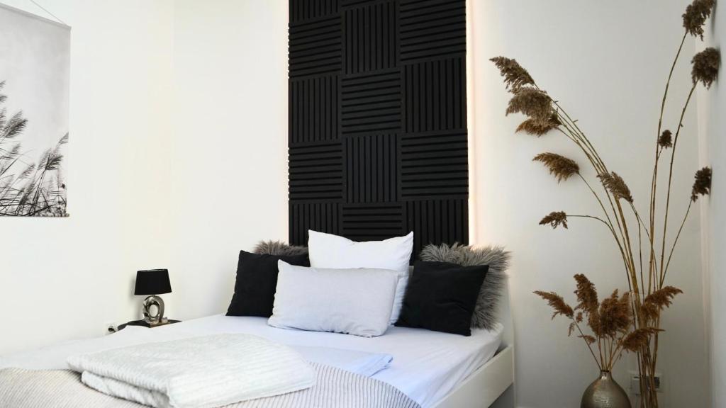 Schlafzimmer mit einem Bett mit schwarzen und weißen Kissen in der Unterkunft Interior Apartments in Kassel Bad Wilhelmshöhe in Kassel