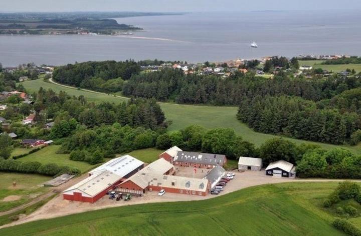 an aerial view of a large barn with the water at Kongshøjgaard in Farsø