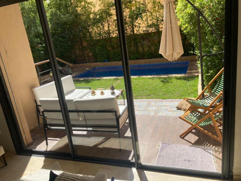Blick auf eine Terrasse mit einer Badewanne durch eine Glasschiebetür in der Unterkunft New villa in Marrakech palmeraie in Marrakesch