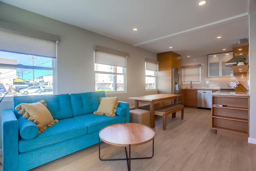 a living room with a blue couch and a kitchen at Ocean Beach Retreat, 3BR Newly Remodeled, Steps to Beach and Boardwalk in San Diego