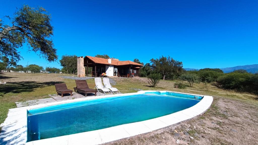 a swimming pool with two chairs and a house at El Cardon - Casa de Campo in Coronel Moldes