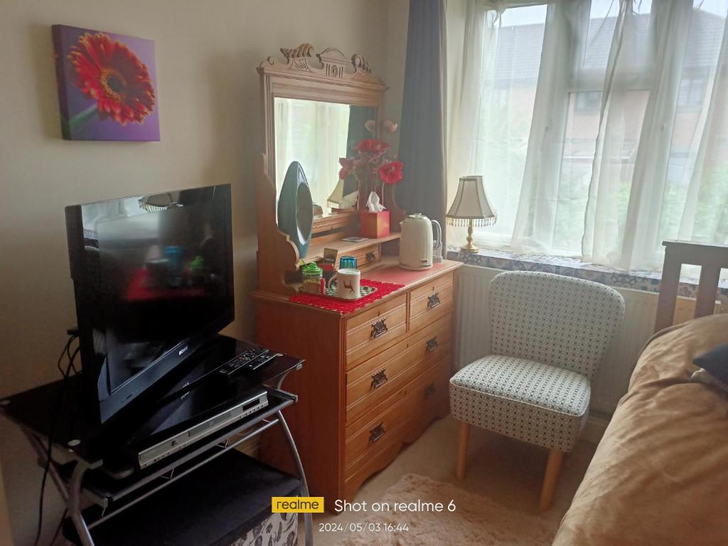 Goldy's place in E17 Room2 في لندن: غرفة معيشة مع تلفزيون وخزانة مع مرآة