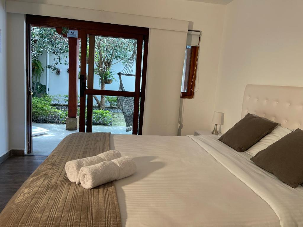 Un dormitorio con una gran cama blanca con toallas. en Once Once Boutique, en Villa de Leyva
